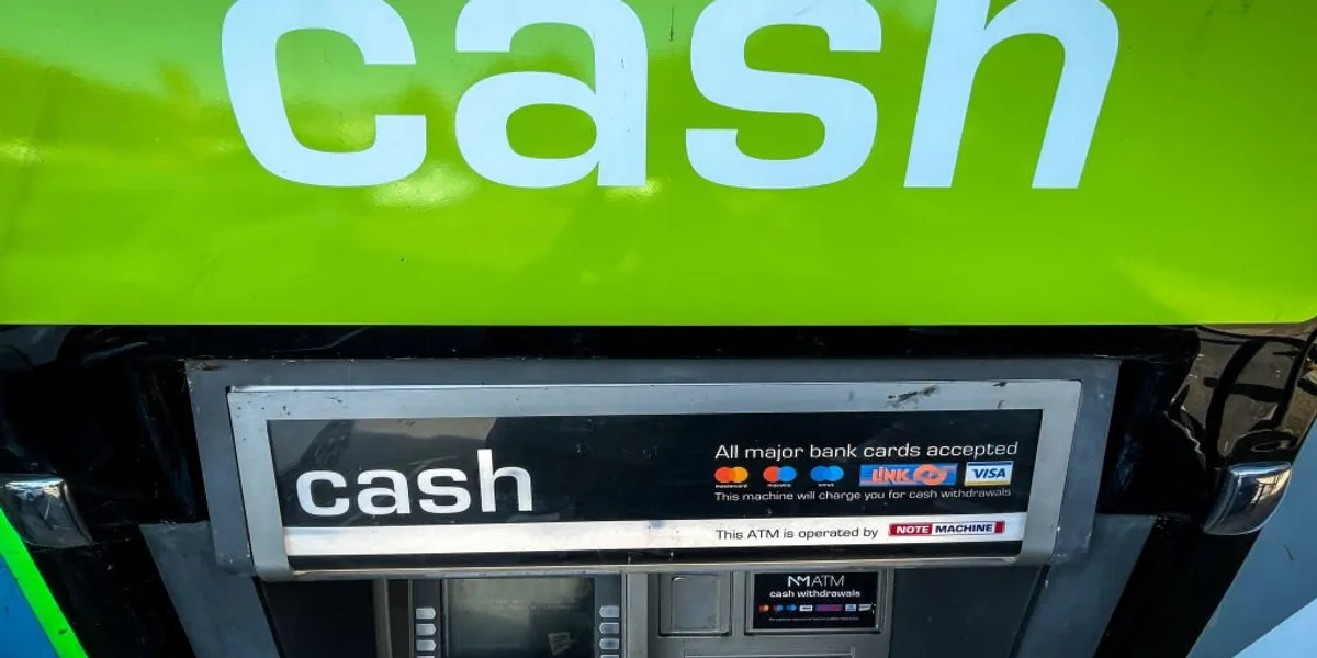 A cash machine under a bright green sign with the word ‘cash’ in large white letters.